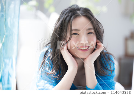 Beautiful woman lying face down with her chin in her hand, looking at the camera. Lying down in the summer sun. Beauty image of the sea, summer sunburn and UV rays. 114043558