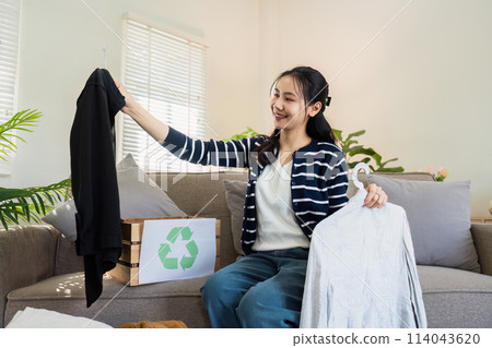 Asian women sort clothes from old clothing box to recycle. Recycling clothes concept 114043620