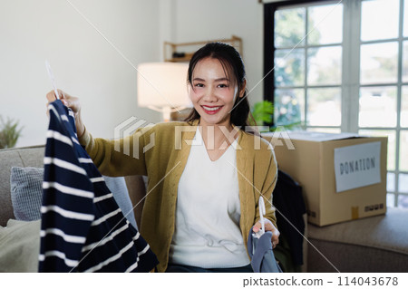 Asian woman select clothes at home to put in a donation box second hand clothes 114043678