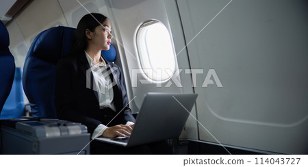 Beautiful Asian businesswoman working with laptop in aeroplane. working, travel, business concept Beautiful Asian businesswoman working with laptop in aeroplane. working, travel, business concept 114043727