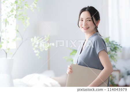 Young woman with laptop computer by the window in a beautiful office, holding a PC and smiling while looking at the camera, copy space on the left Young woman with laptop computer by the window in a beautiful office, holding a PC and smiling while looking at the camera, copy space on the left 114043979