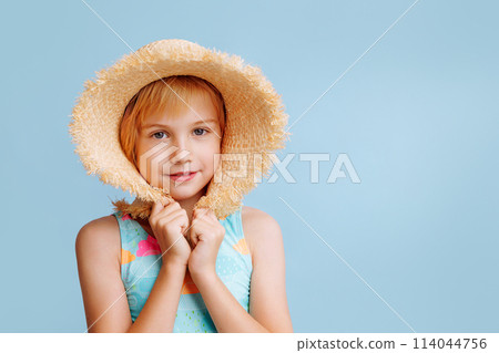 A young girl wearing a straw hat and a blue and pink swimsuit A young girl wearing a straw hat and a blue and pink swimsuit 114044756