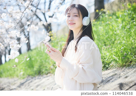 A woman listening to music under the cherry blossoms 114046538