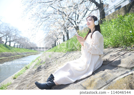 A woman listening to music under the cherry blossoms 114046544