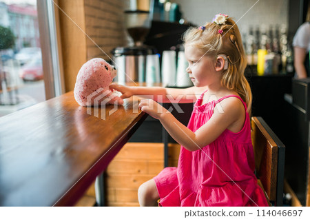 Child girl walks and have fun outdoor with cochlear implant on the head. Hearing aid and treatment concept. Inclusion and disability. Child girl walks and have fun outdoor with cochlear implant on the head. Hearing aid and treatment concept. Inclusion and disability. 114046697