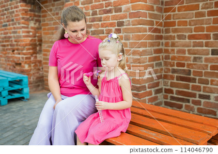 Blonde little girl with cochlear implant playing with her mother outdoor. Hear impairment deaf and health concept. Disability and inclusion. Copy space 114046790