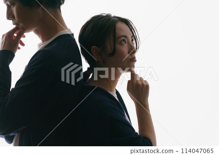 Silhouette of a man and woman standing back to back 114047065