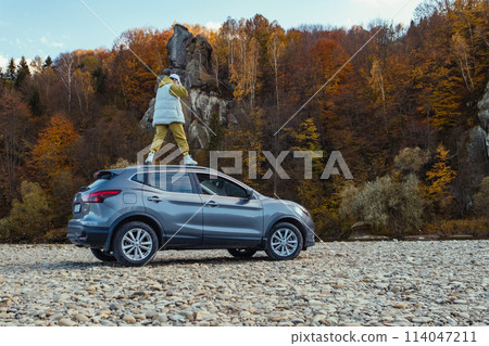 happy woman at car roof enjoying the view of autumn river in carpathian mountains 114047211