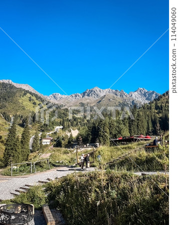 A stunning view of a majestic mountain range with a quaint building and lush trees in the foreground, showcasing natures beauty A stunning view of a majestic mountain range with a quaint building and lush trees in the foreground, showcasing natures beauty 114049060