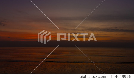 silhouettes A serene sunset over the beach, the sky of orange and casting 114049996