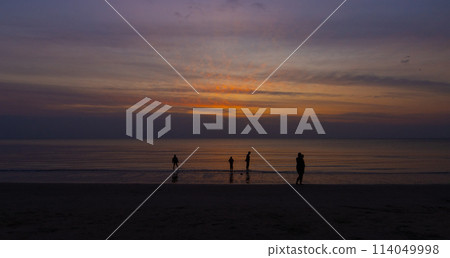 Silhouettes Beach Evening Glow with People Activity and Walking by the Sea 114049998