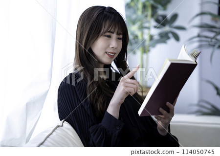 Young woman reading on the sofa on holiday 114050745