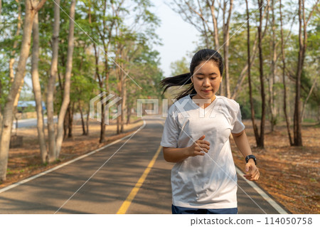 Young woman running alone in the morning at local running park in the summer Young woman running alone in the morning at local running park in the summer 114050758