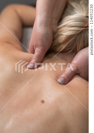 A woman undergoing a massage of the cervical-collar area. 114051230