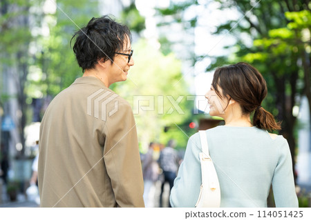 一對年輕夫婦微笑著在城裡散步的後視圖 114051425