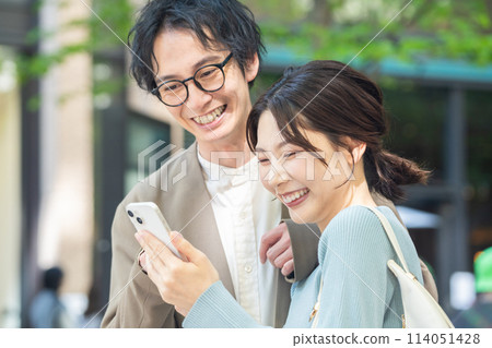 夫婦微笑著使用智慧型手機 114051428