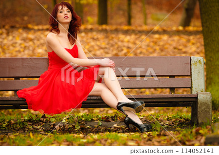 woman red dress sitting on bench in autumn park 114052141