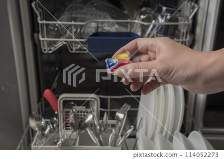 Woman putting detergen kapsul into open dishwasher 114052273