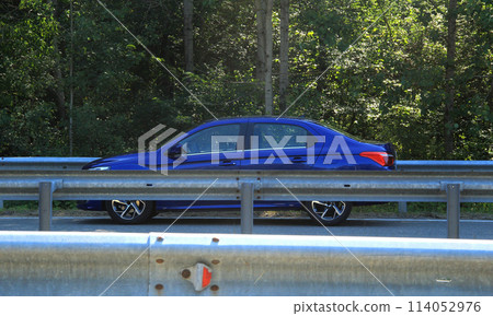 Car on the road behind the metal highway fence  114052976