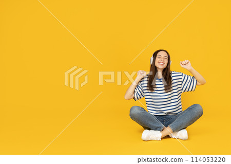 A girl in headphones listens to music, on a yellow background. A girl in headphones listens to music, on a yellow background. 114053220