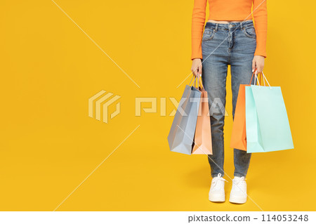Young girl with shopping bags on a yellow background. Young girl with shopping bags on a yellow background. 114053248