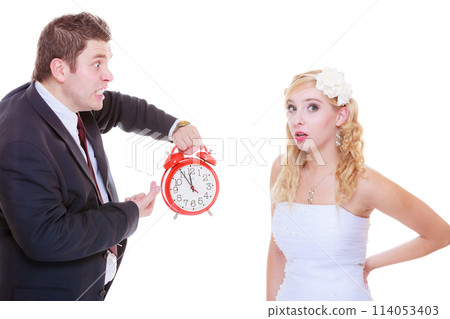 Groom holding big red clock yelling and bride 114053403