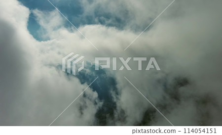 Flying through clouds between mountains 114054151