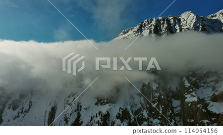 Flying through clouds between mountains Flying through clouds between mountains 114054156