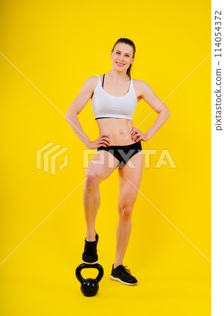 Sport, active lifestyle concept. Smiling strong and slim fitness female athlete holding kettlebell Sport, active lifestyle concept. Smiling strong and slim fitness female athlete holding kettlebell 114054372