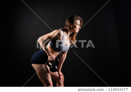 Sport, active lifestyle concept. Smiling strong and slim fitness female athlete holding kettlebell 114054377