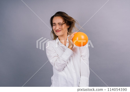 Portrait of beautiful woman with a ballon in hands on grey background in studio 114054390