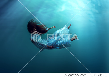 Meditation app cover. Young girl with red hair, in dress gracefully falling down the ocean, showing eternal life in marine surroundings 114054555