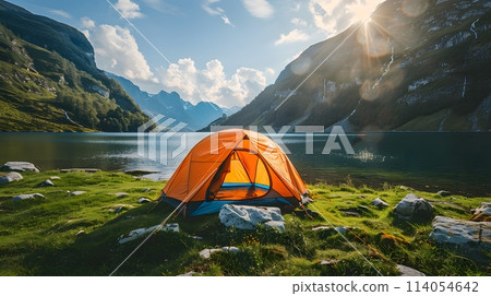 Beautiful campsite. Warm sunlight shine through the mountains onto green field. The lake and tranquil valley are visible in the background. We will experience an adventure amidst the beauty of nature. 114054642