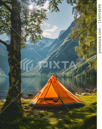 Beautiful campsite. Warm sunlight shine through the mountains onto green field. The lake and tranquil valley are visible in the background. We will experience an adventure amidst the beauty of nature. 114054649