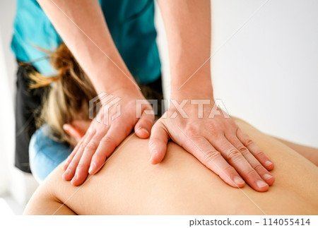 Massage therapist doing back massage in spa Salon. Healthcare and relaxation procedures. 114055414