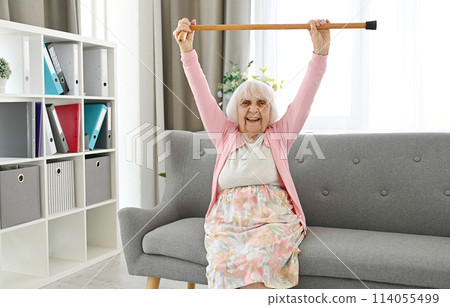 Elderly Woman Lifts Walking Cane Upwards Symbolizes Victory Over Disease 114055499