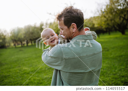 Father holding little baby, playing, having fun during warm spring day. Father's day concept. Father holding little baby, playing, having fun during warm spring day. Father's day concept. 114055517
