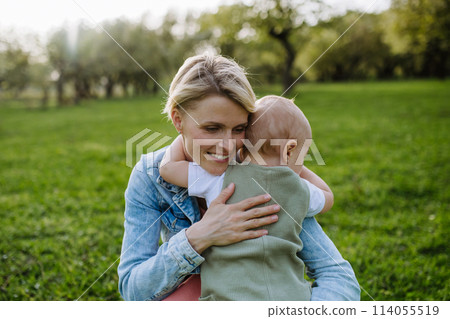 Portrait of beautiful mature first time mother with small toddler, outdoors in spring nature. Portrait of beautiful mature first time mother with small toddler, outdoors in spring nature. 114055519
