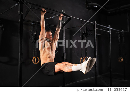Man performing L-sit pull ups on bars, challenging bodyweight exercise. Bodyweight workout for physical and mental health. Man performing L-sit pull ups on bars, challenging bodyweight exercise. Bodyweight workout for physical and mental health. 114055617