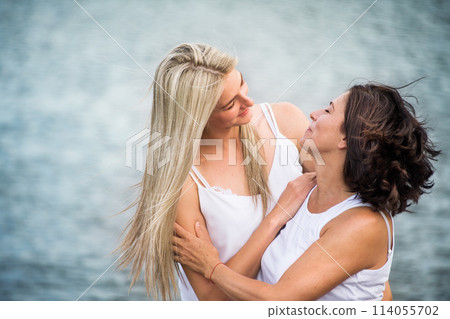 Adult daughter spending time with her mother outdoors. Beautiful daughter holding each other lovingly, hugging. Unconditional, deep maternal love, Mother's Day. 114055702