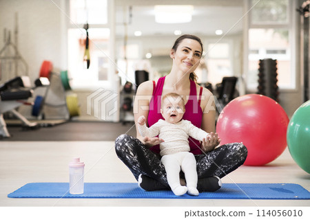 Portrait of new mom on group exercise class in gym. Moms staying active while boding with babies. Portrait of new mom on group exercise class in gym. Moms staying active while boding with babies. 114056010