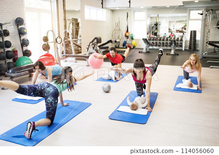 Group exercise class, mother working out with baby in gym. Moms staying active while boding with babies. 114056060