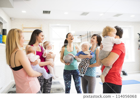 Group exercise class, mother working out with baby in gym. Moms staying active while boding with babies. New parent friends. Group exercise class, mother working out with baby in gym. Moms staying active while boding with babies. New parent friends. 114056068