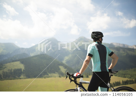 Rear view of cyclist admire mountains and beautiful nature, standing by bicycle. Concept of healthy lifestyle. Rear view of cyclist admire mountains and beautiful nature, standing by bicycle. Concept of healthy lifestyle. 114056105