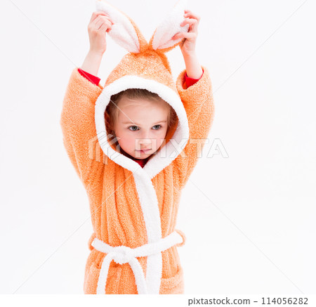 Lovely kid playing in a bathrobe with bunny ears, pretending she is a rabbit 114056282