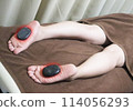 Woman receiving hot stone treatment 114056293