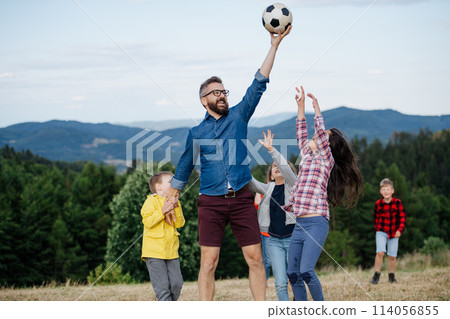 Young students playing with teacher outdoors, in nature, during field teaching class, having fun. Dedicated teachers during outdoor active education. 114056855