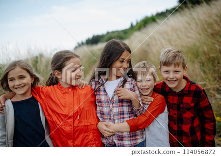 Portrait of young classmates, students during biology field teaching class, standing in the middle of meadow. Learning about ecosystem, ecology. 114056872