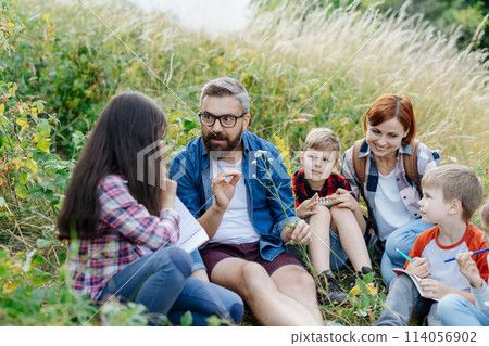 Young students learning about nature, forest ecosystem during biology field teaching class, observing wild plants. Dedicated teachers during outdoor active education. 114056902
