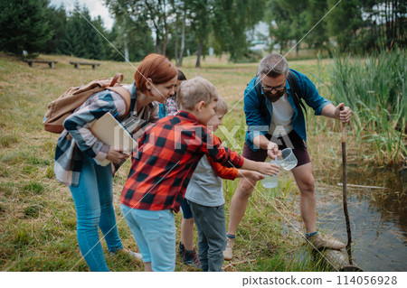 Teacher showing lake water to school children, during field teaching class. Outdoor active education helping young student to learn about ecosystem. 114056928